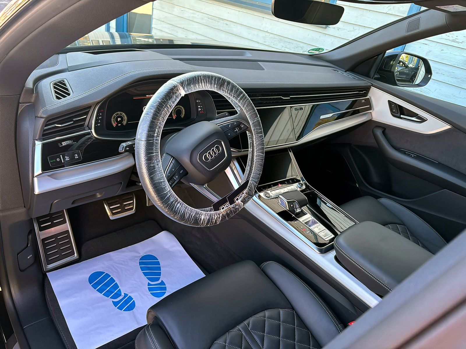 Aufbereitetes Cockpit eines Audi Q8 mit Lenkradschoner und Einmal-Fußmatte von DIST Autopflegeservice