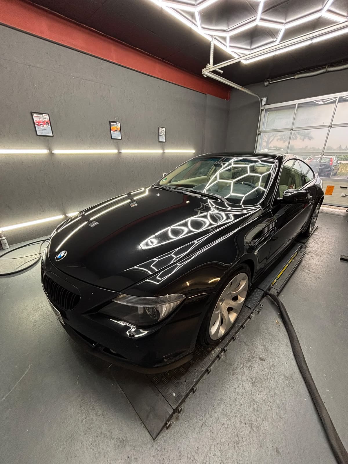 Schwarzes BMW 6er Coupé nach der Politur, klare Lichtreflexe auf Motorhaube und Flanke