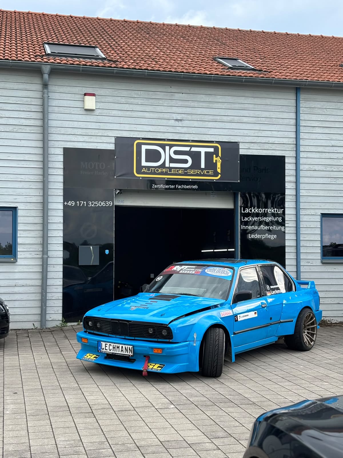 Hellblauer BMW E30 Driftwagen vor dem Betriebsgebäude von DIST Autopflegeservice