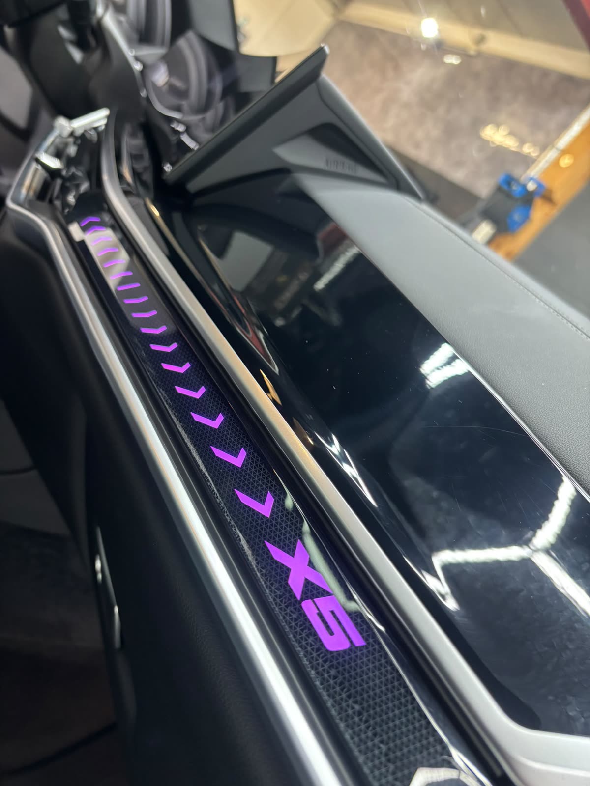 Beleuchtete Einstiegsleiste eines BMW X5 mit violettem Schriftzug