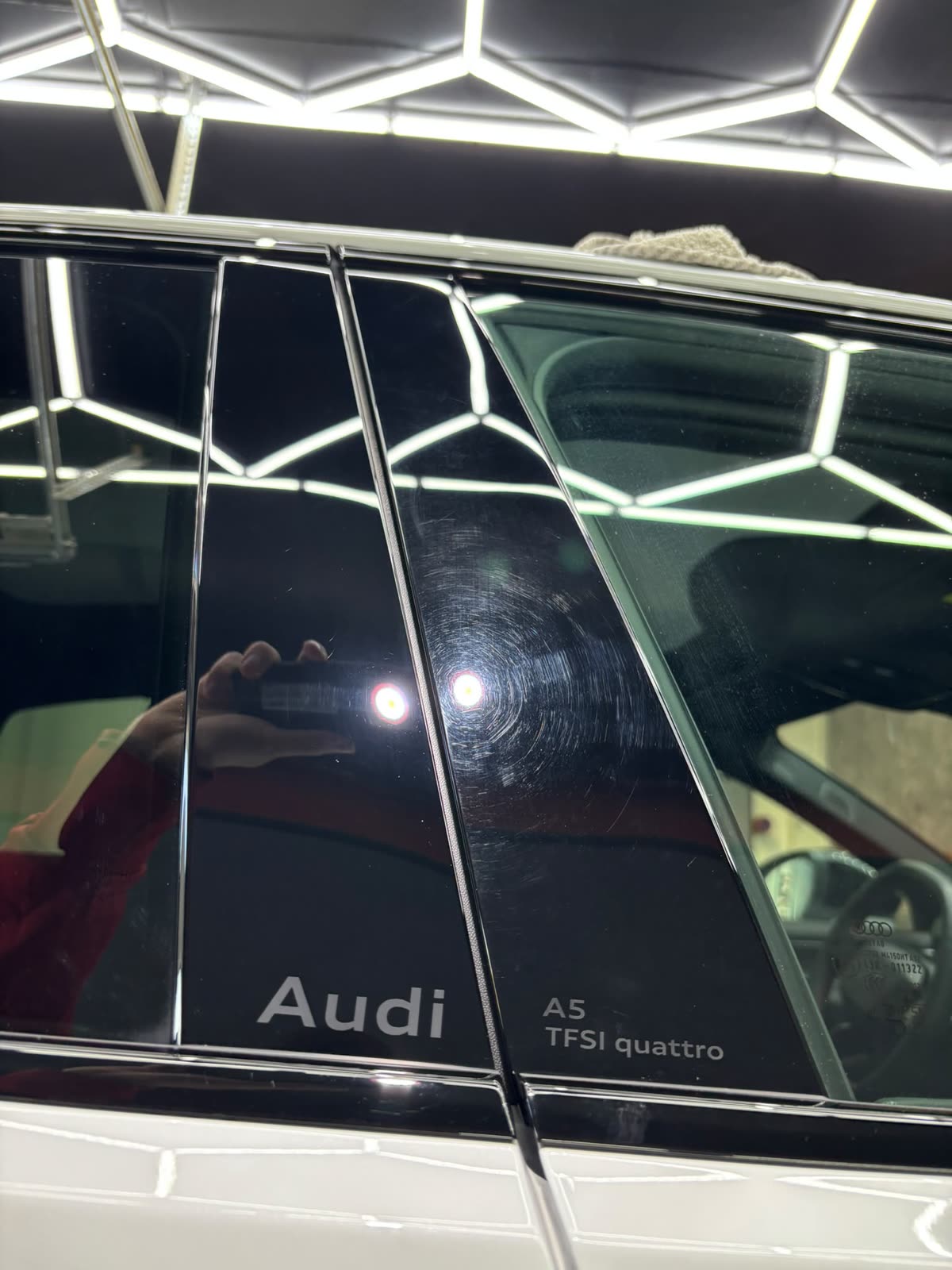 Prüfleuchte legt feine Kratzspuren im Klavierlack einer Audi-B-Säule offen
