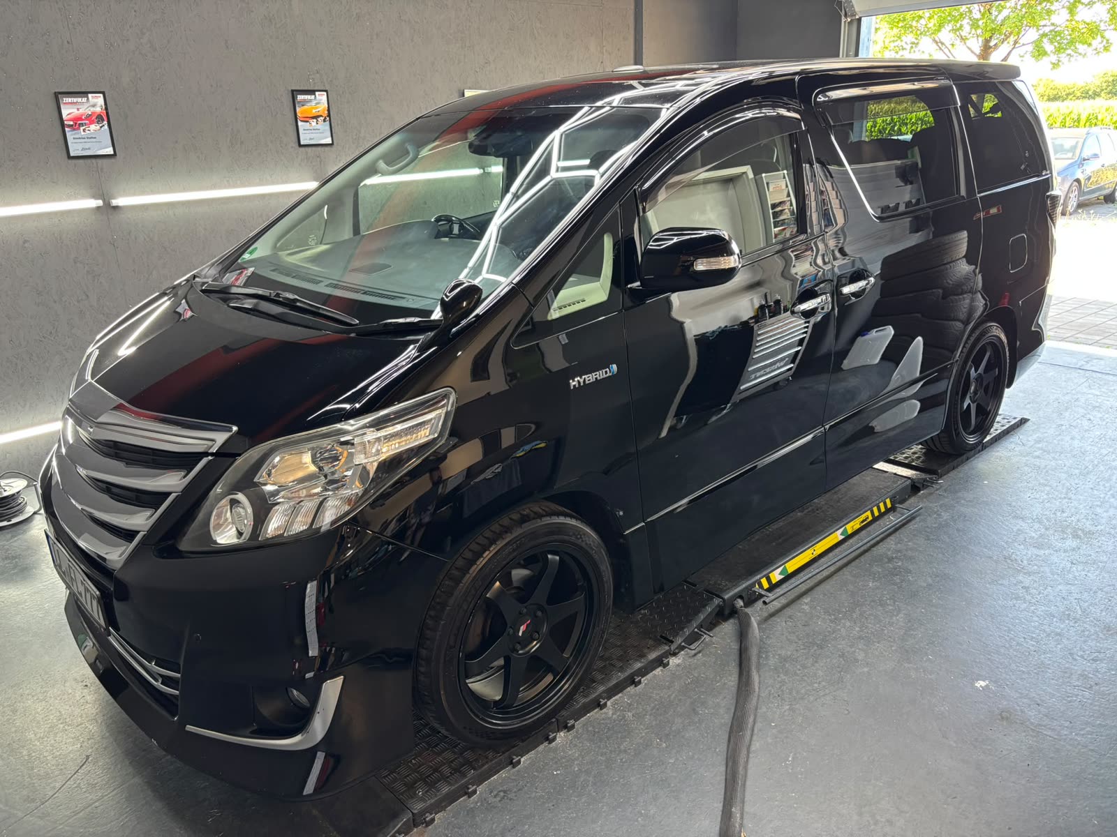 Schwarzer Toyota Alphard Hybrid in der Halle, tiefer Glanz auf der gesamten Flanke